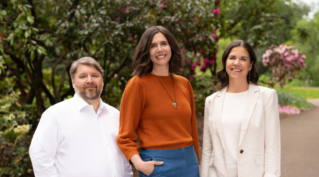 three mediators standing outdoors, smiling at the camera